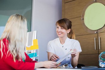 Dental team member talking with patient while sitting at desk