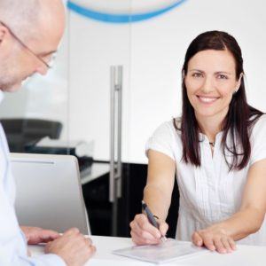 Man talking to dental team member at reception desk