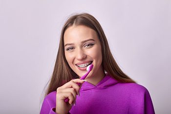 Young woman with braces holding a toothbrush