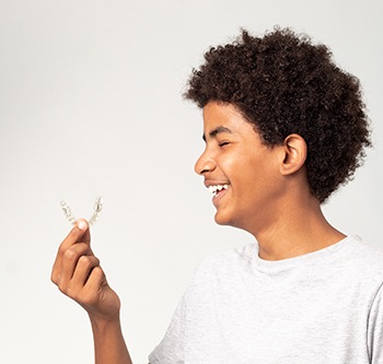 Happy teen boy holding Invisalign aligner