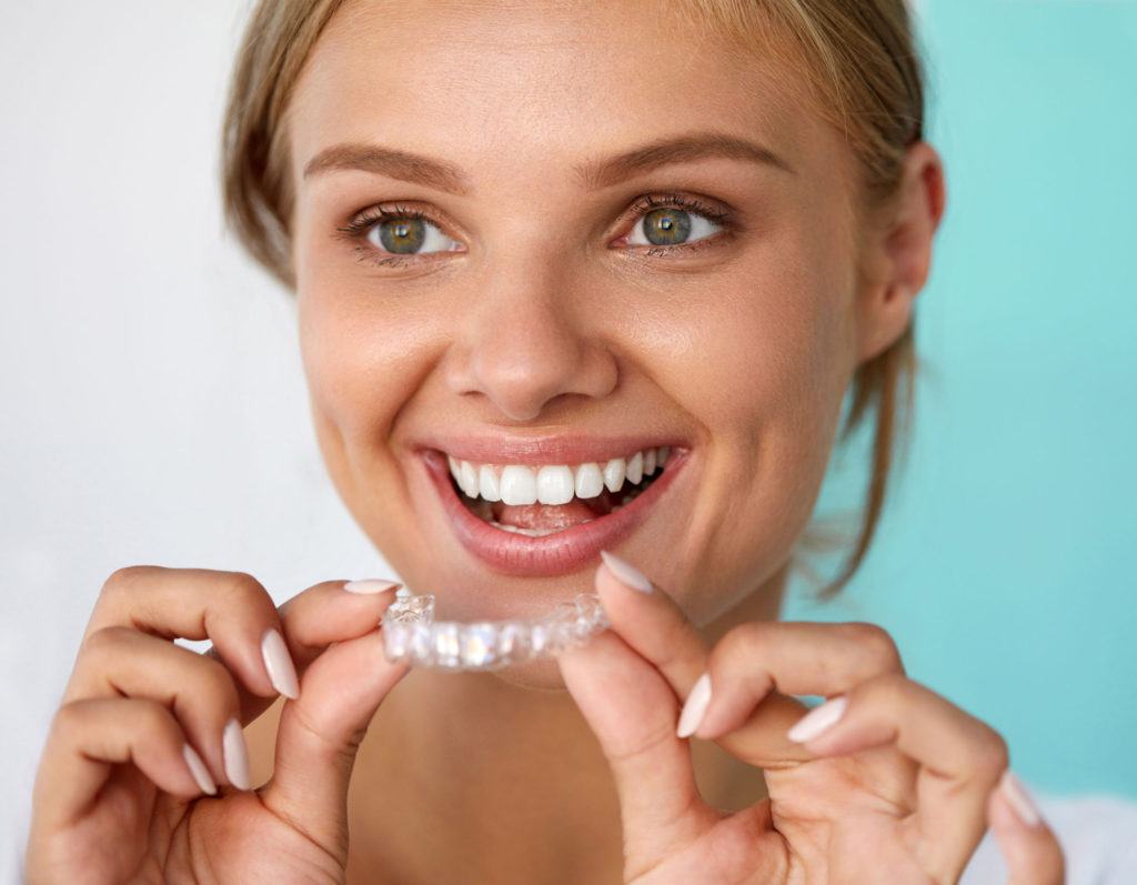 Woman placing Invisalign tray over her teeth