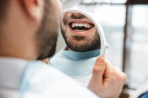 Man looking at his teeth in the mirror